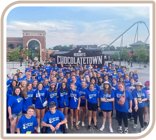 A group of people wearing blue shirts and standing in front of a sign.