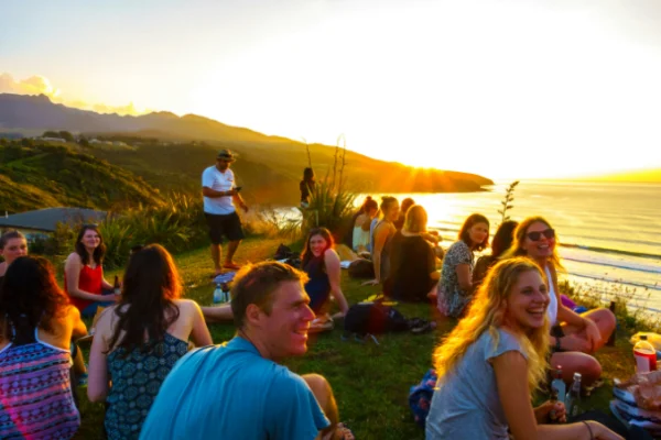 A group of people sitting on the grass near water.