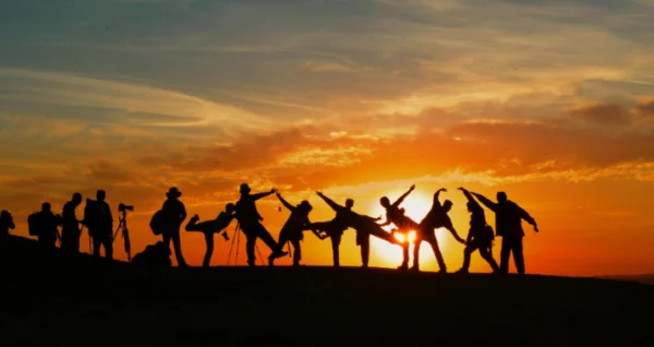 A group of people standing in front of the sun.