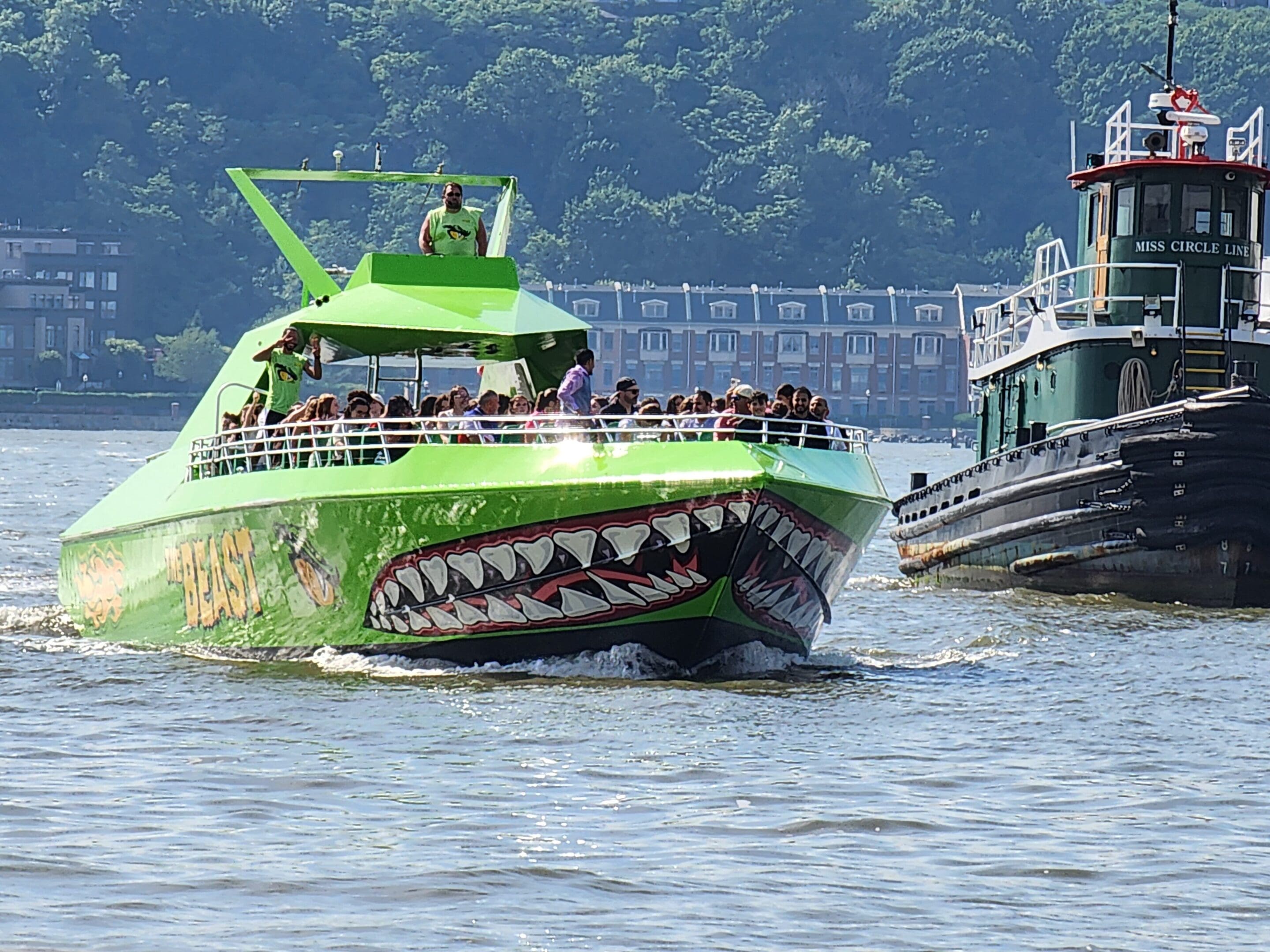 A green boat with a shark mouth on it and another boat in the water.