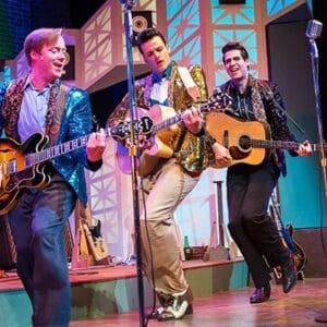 Three men are playing guitar and singing on stage.