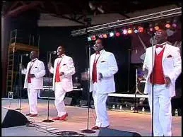 A group of men in white suits singing on stage.