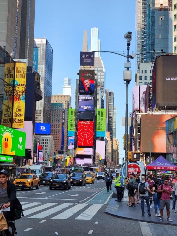 A busy city street with many people and taxis.