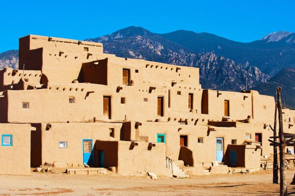 Pueblo adobe buildings, mountain backdrop.